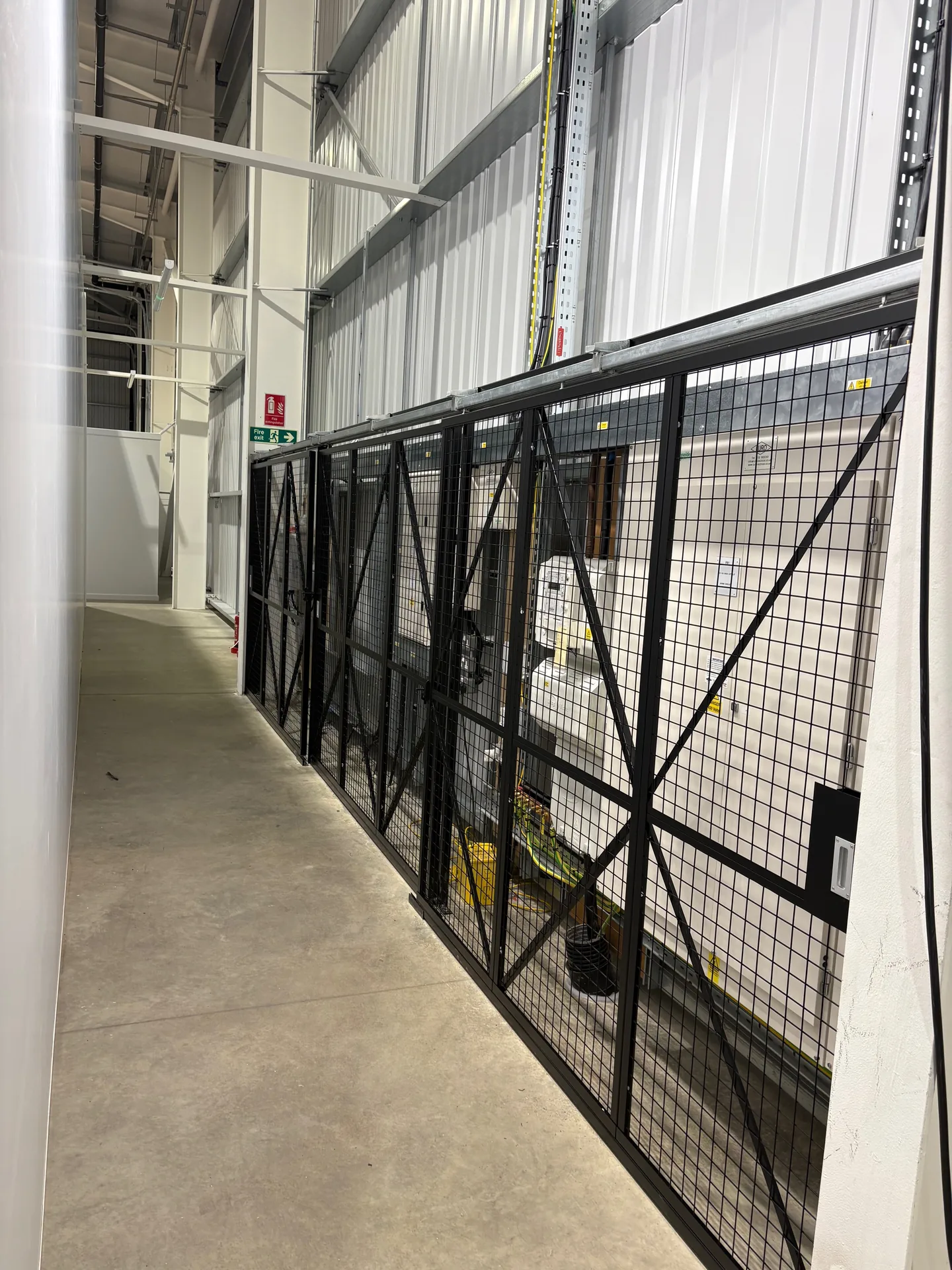 Black mesh security cage with sliding doors around electrical panels in Leicester