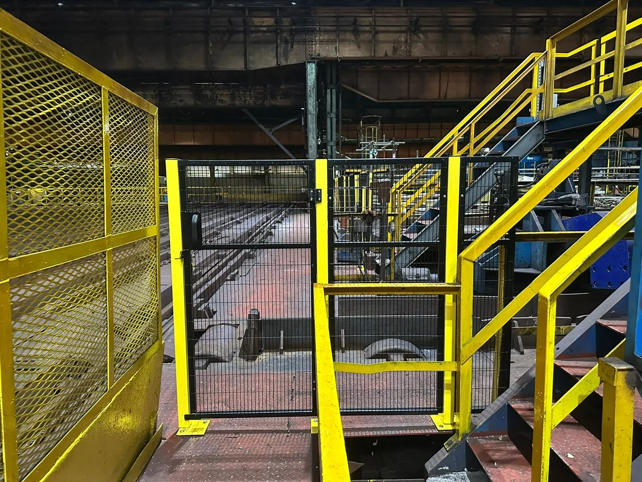 Black and yellow machine guarding door beside steel stairs at a Sheffield site